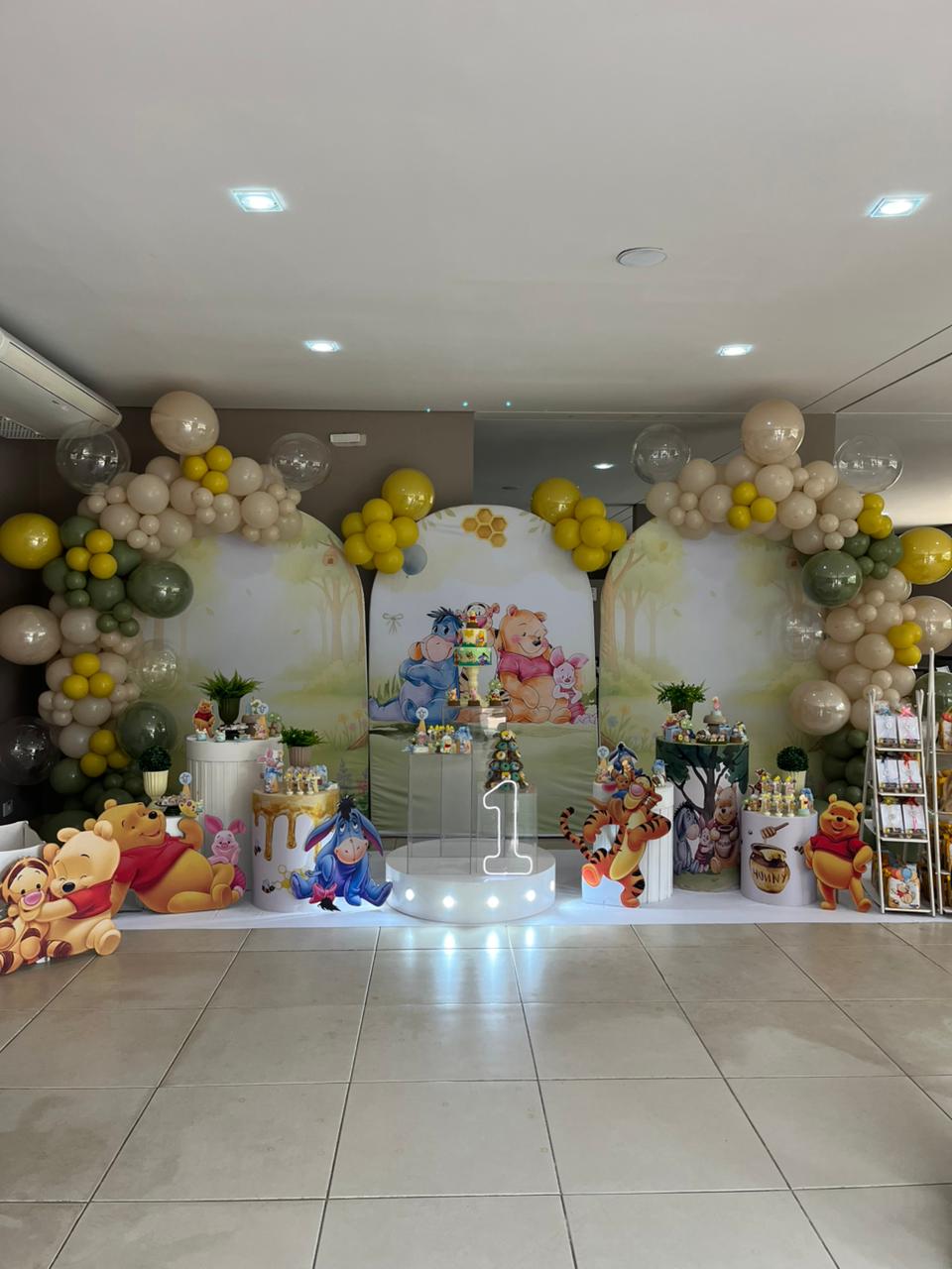 Decoração de festa infantil temática do Ursinho Pooh com balões em tons neutros e personagens